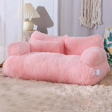 A cozy room features KittyNook's Luxury Lounge Pet Sofa Bed, resting on a shaggy rug beside a lamp and woven wall hanging.